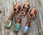 A close up view of Labradorite Dread Beads Set of 3 on a wooden background.