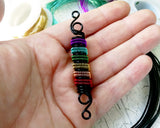 A top view of a Rainbow Pride Dread Bead in hand.