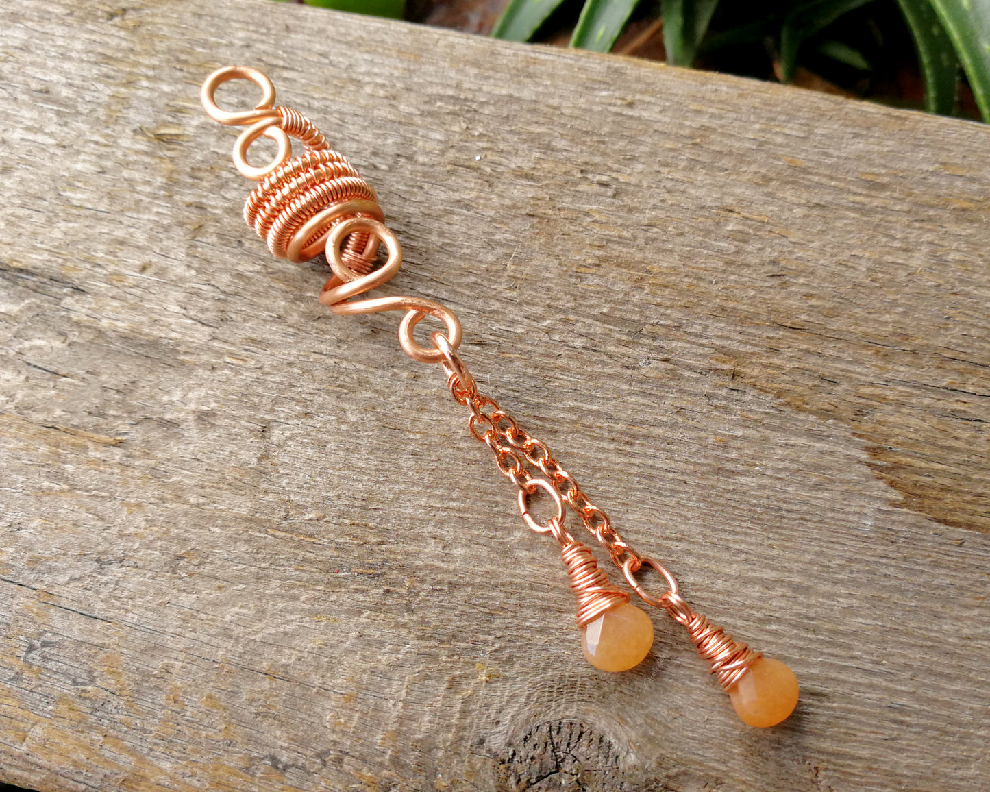 An aventurine hair jewel on a wood background.