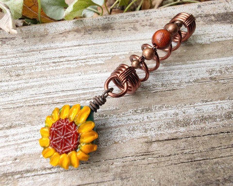 Glass Sunflower Dread Bead on a wood background.