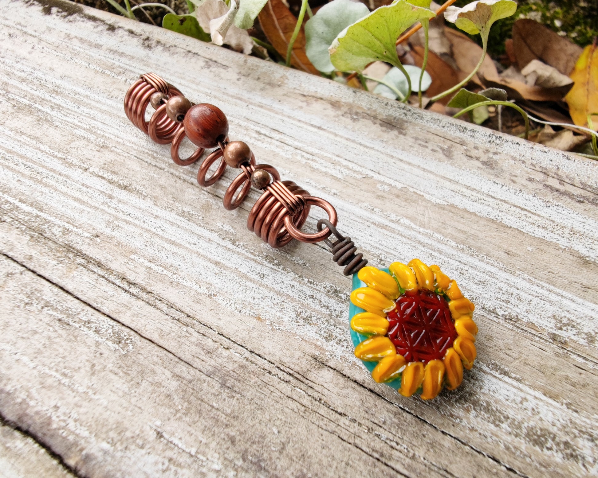 Glass Sunflower Dread Bead on a wood background.