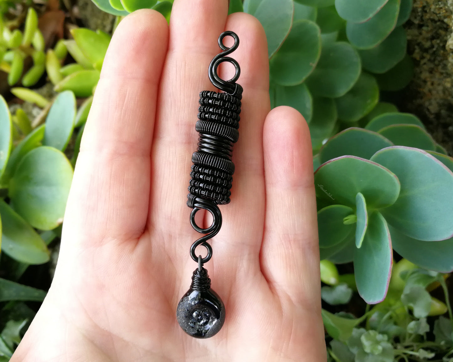 Black stardust glass dread bead in hand for reference.
