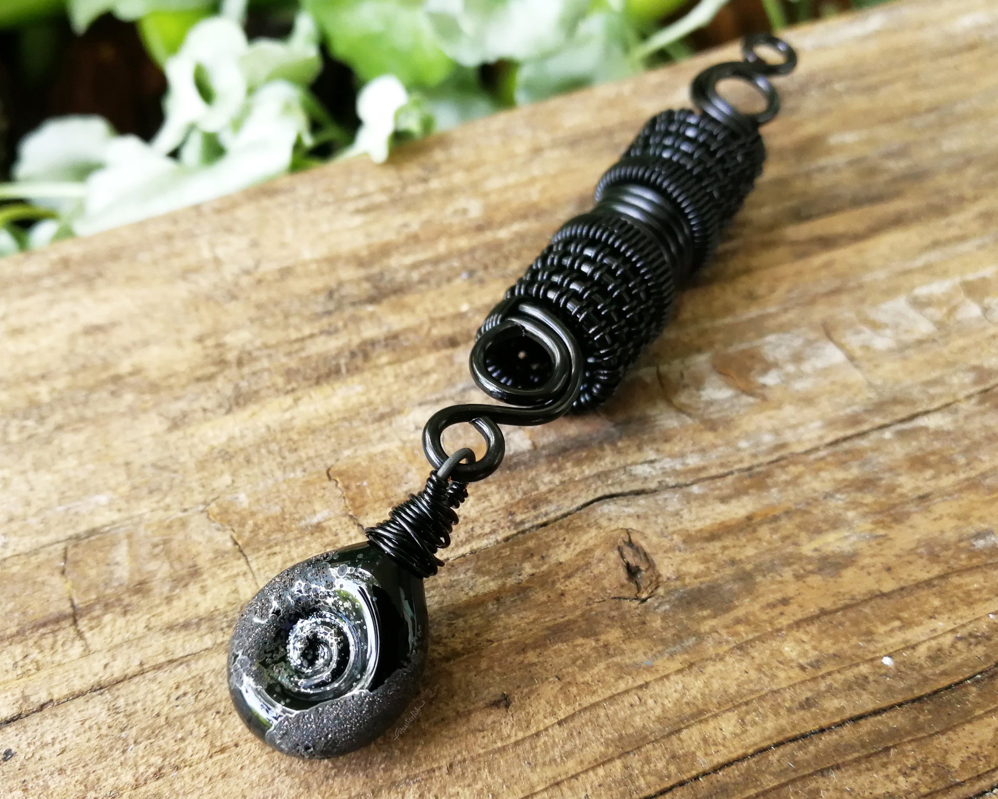 Black stardust glass dread bead on a wood backdrop.