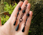 Set of three black dreadlock beads held in hand to show scale.