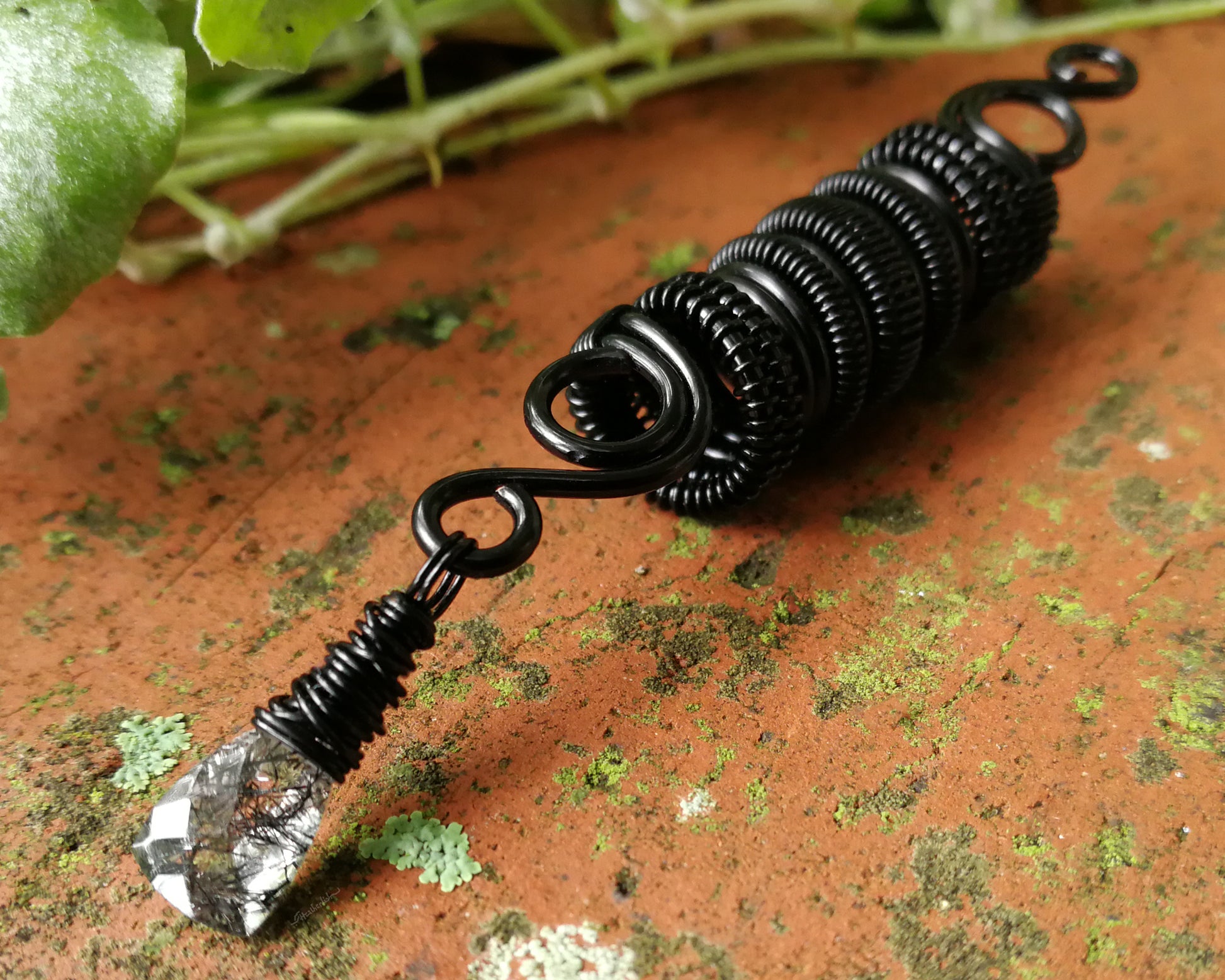 Black rutilated dread bead on wood background.