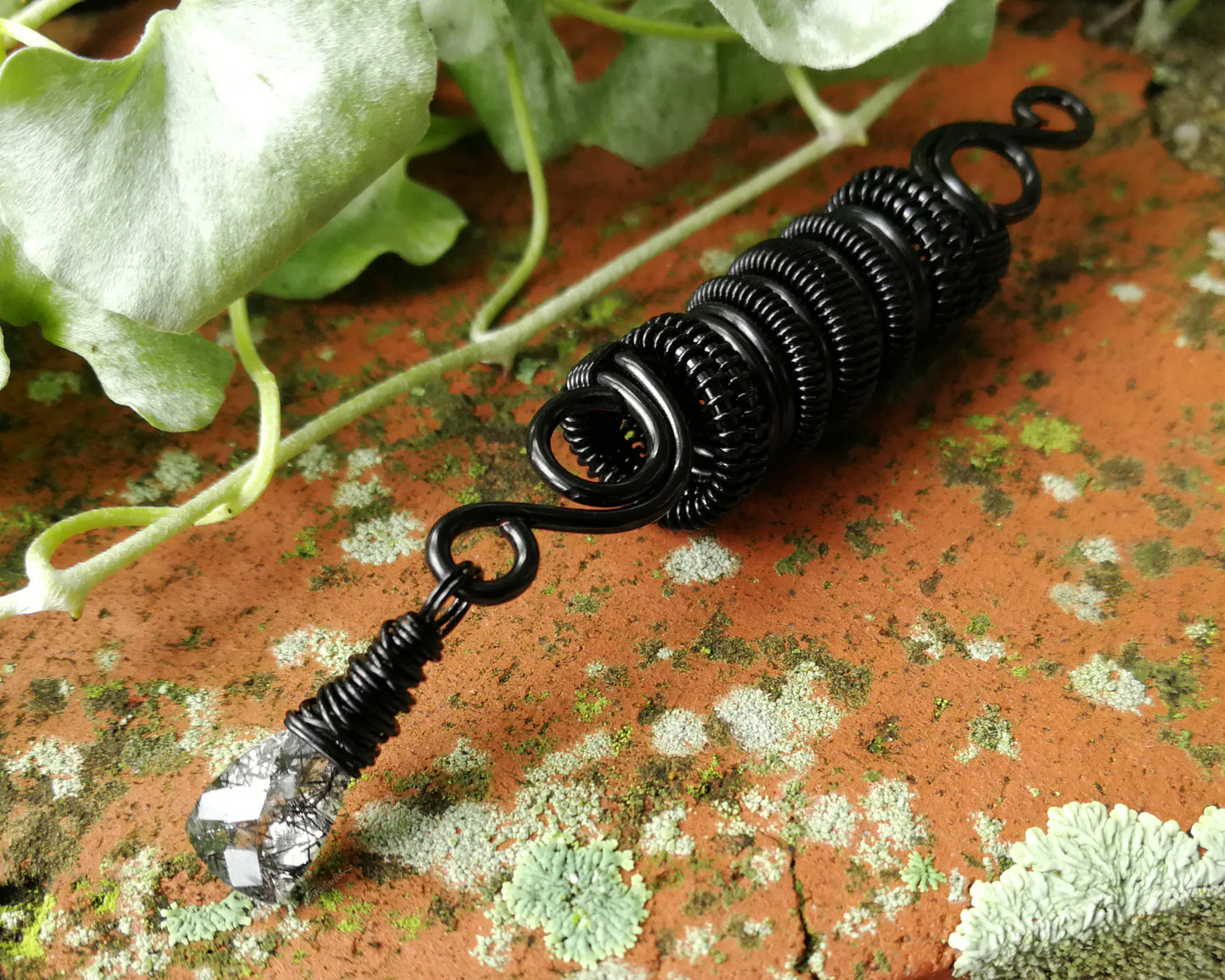 Black rutilated dread bead on wood background.
