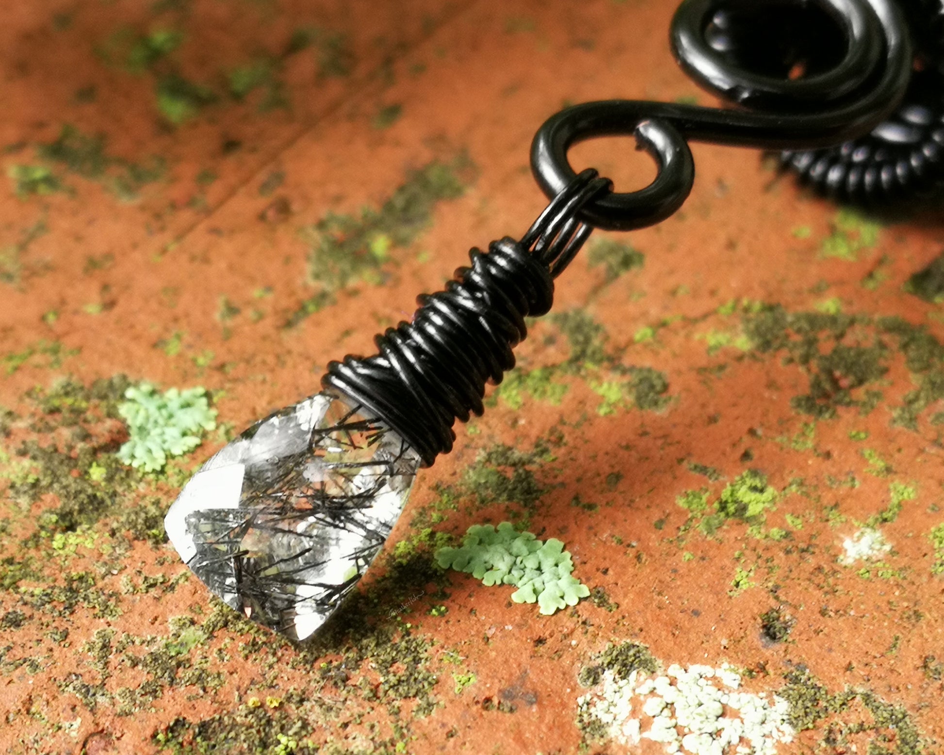 Black rutilated dread bead on wood background.