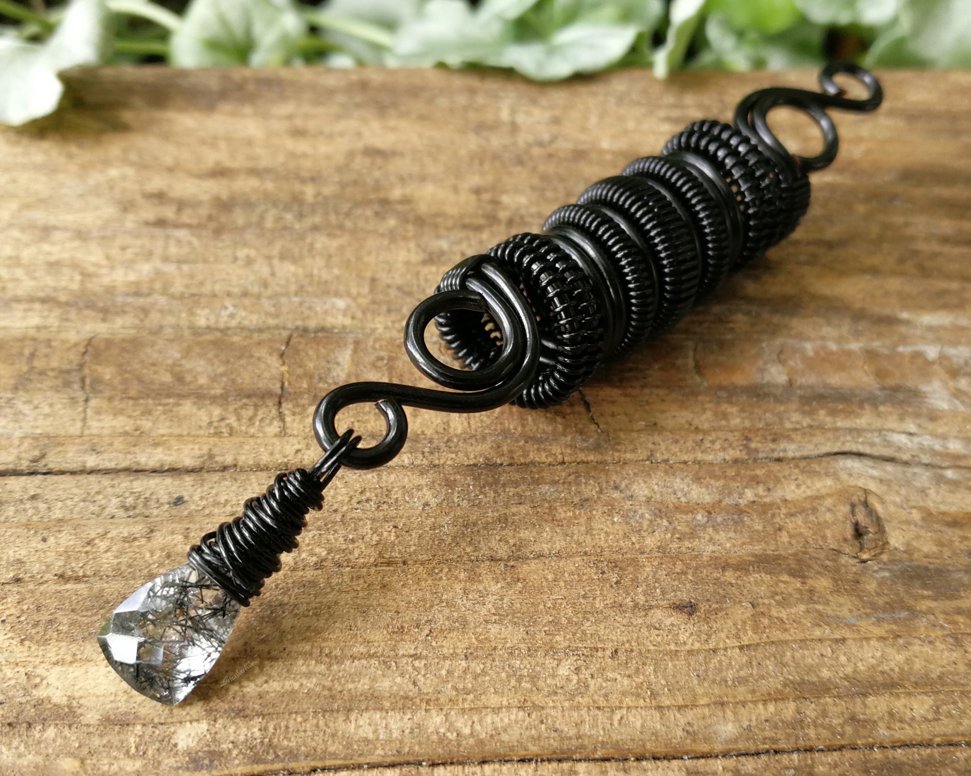 Black rutilated dread bead on wood background.
