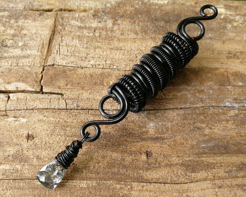 Black rutilated dread bead on wood background.