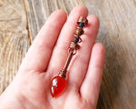 Red onyx fire dread bead held in hand to show scale.
