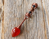 Red onyx fire dread bead on wood background.