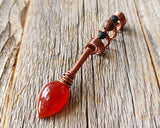 Red onyx fire dread bead on wood background.