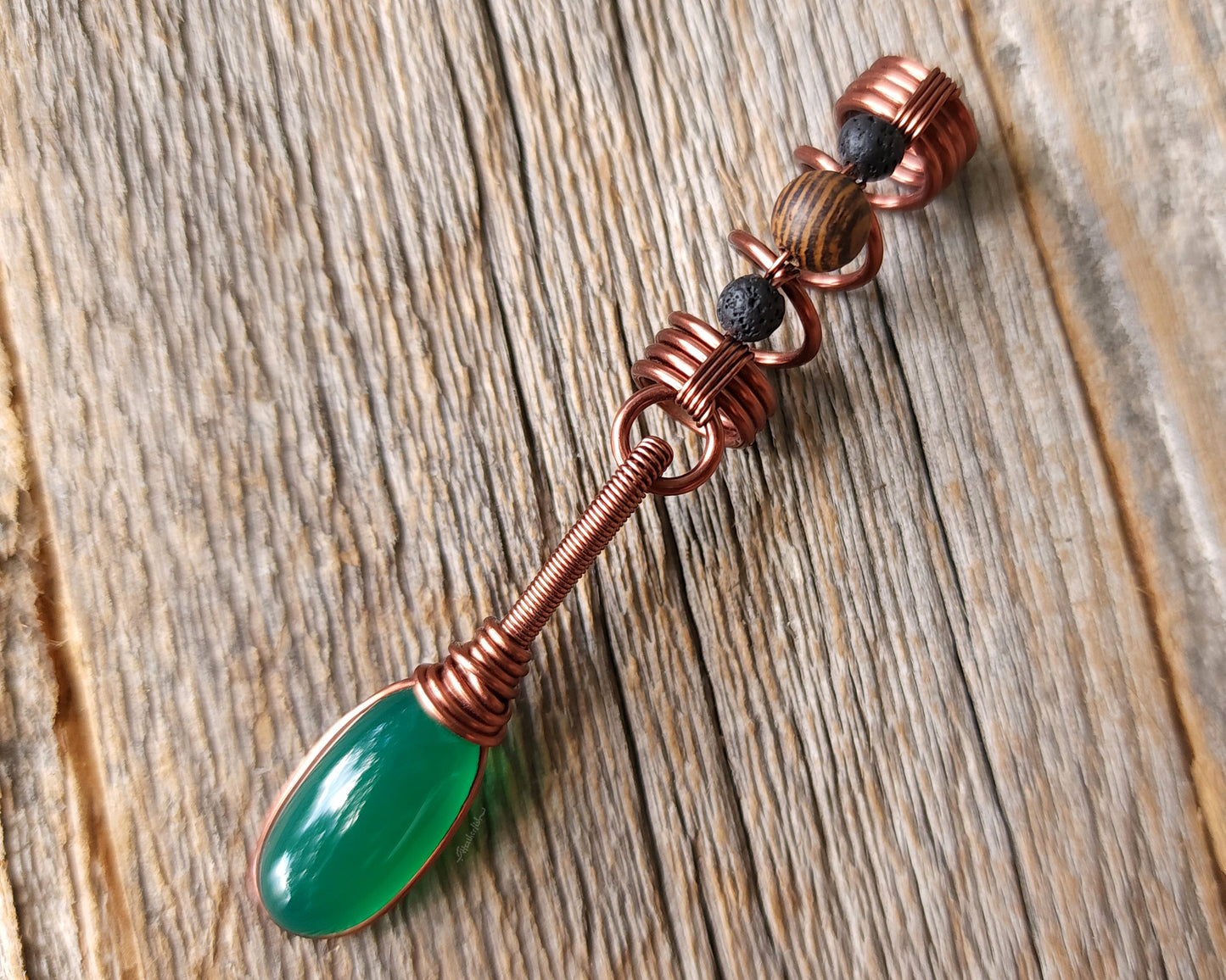 Green onyx earth dread bead on wood background.