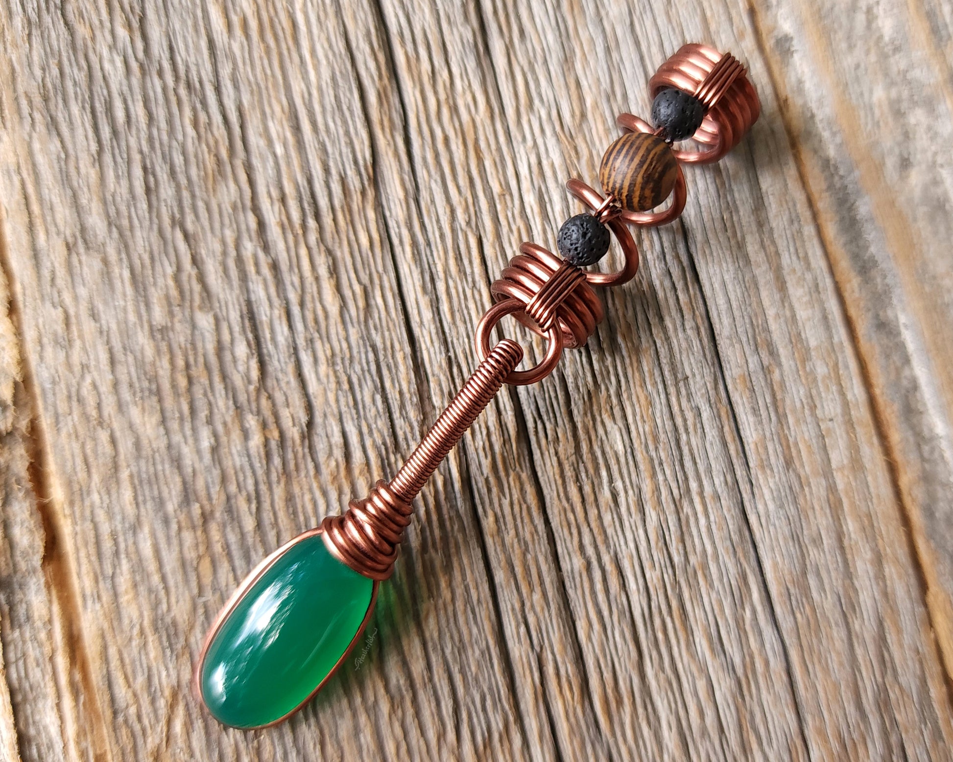 Green onyx earth dread bead on wood background.