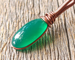 Green onyx earth dread bead on wood background.
