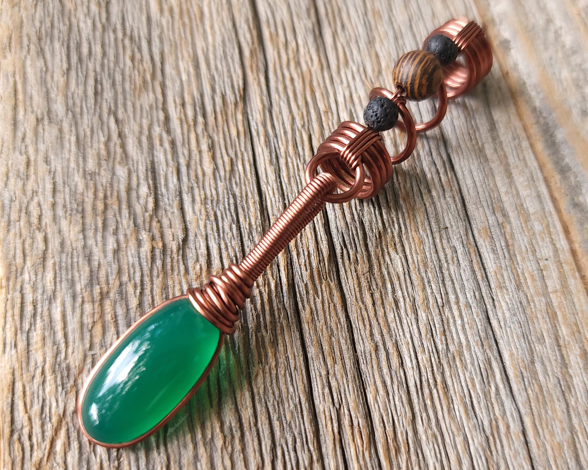 Green onyx earth dread bead on wood background.
