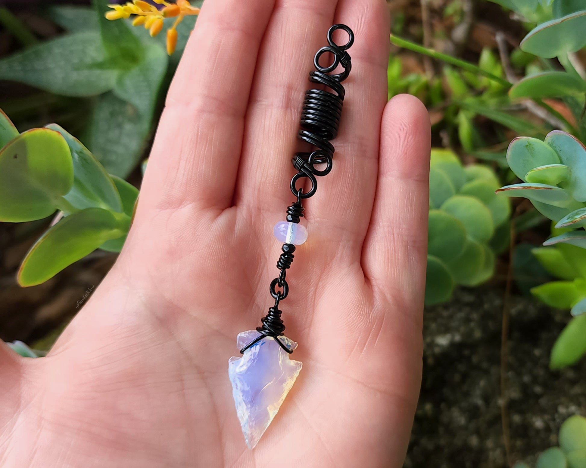 Glass Arrowhead Dread Bead held in a hand to show scale.