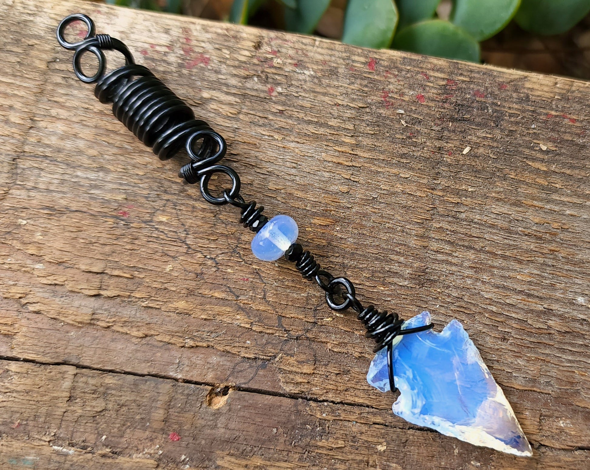 Glass Arrowhead Dread Bead on a wood background.