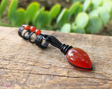 Red Onyx Dread Bead on wood background.