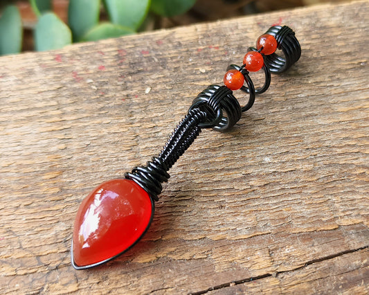 Red Onyx Dread Bead on wood background.