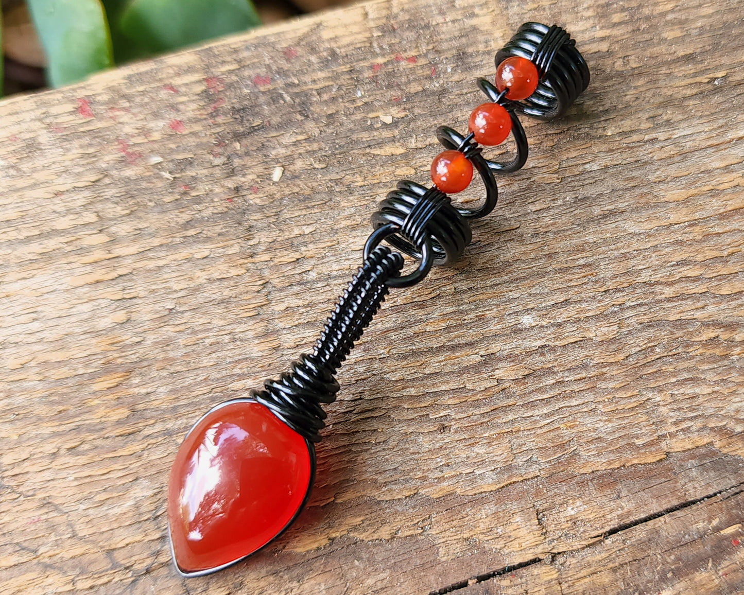 Red Onyx Dread Bead on wood background.