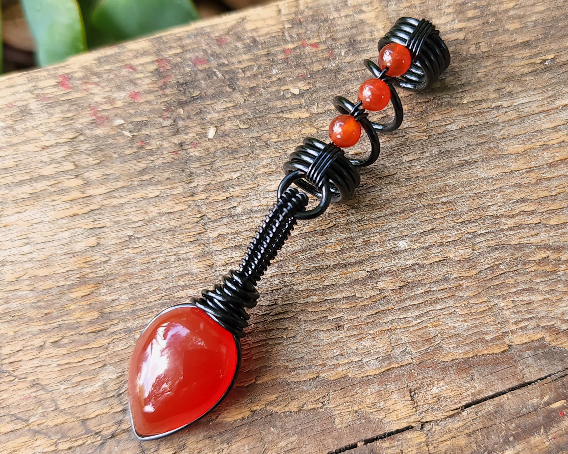 Red Onyx Dread Bead on wood background.