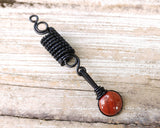 Banded Red Jasper Loc Bead on wood background.