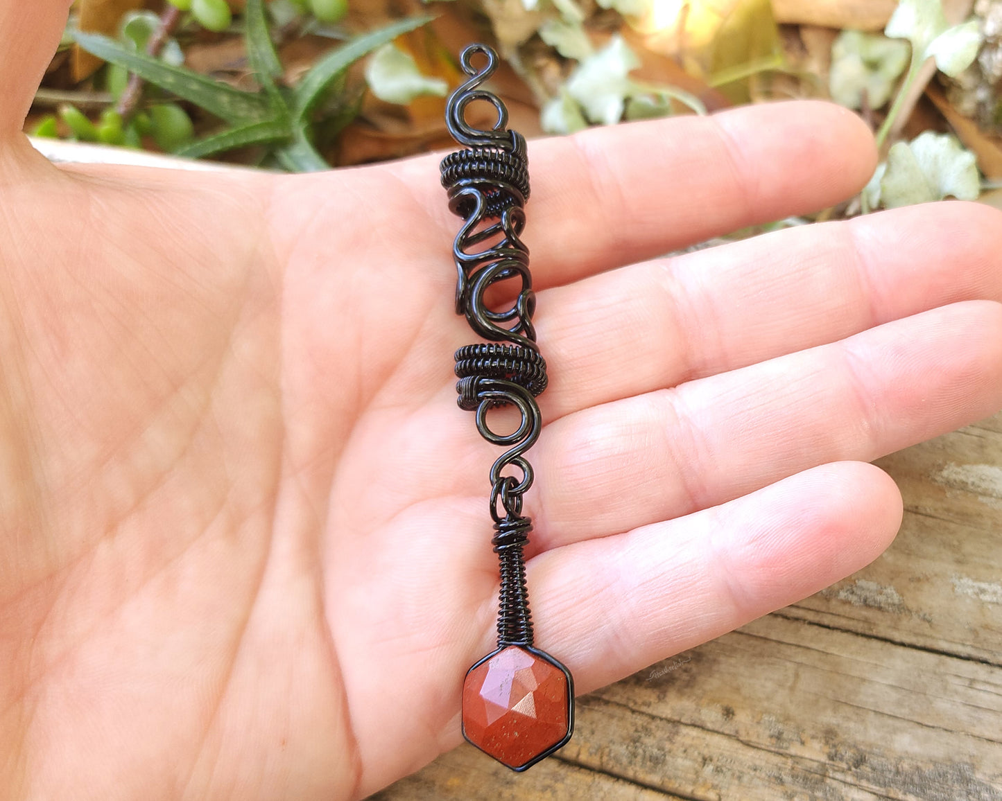 Jasper squiggle loc jewelry held in hand to show scale.