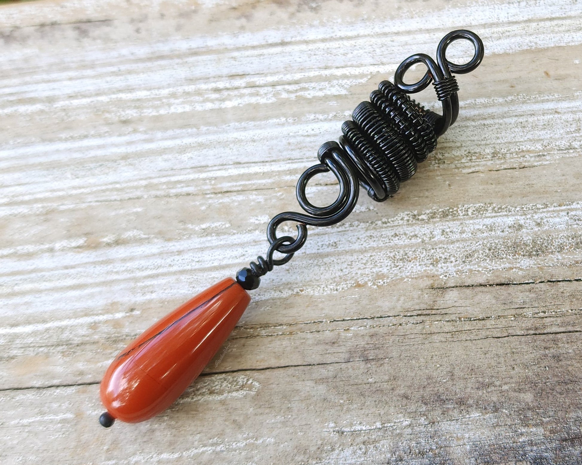 Red Jasper Tear Drop Loc Bead on a wood background.