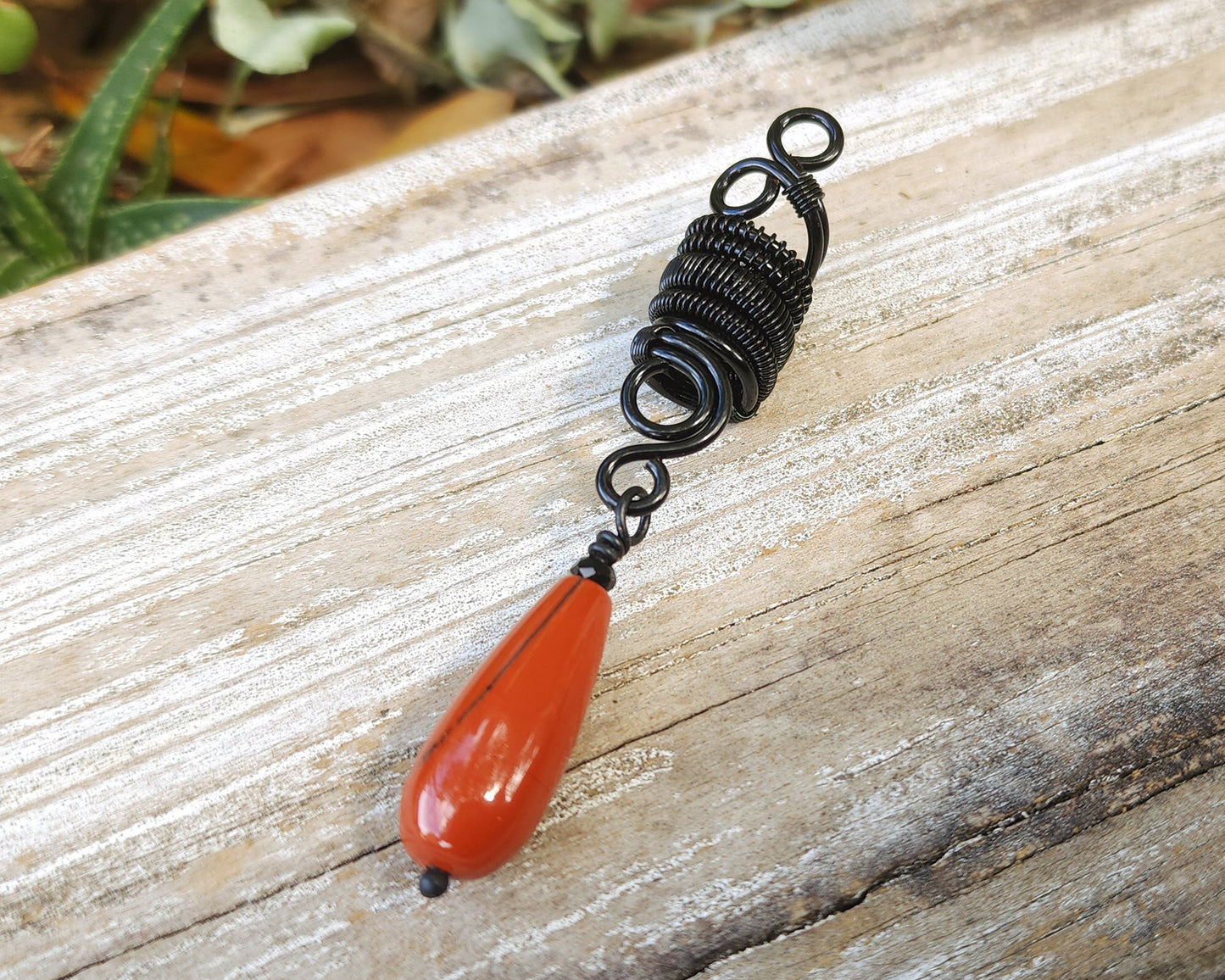 Red Jasper Tear Drop Loc Bead on a wood background.