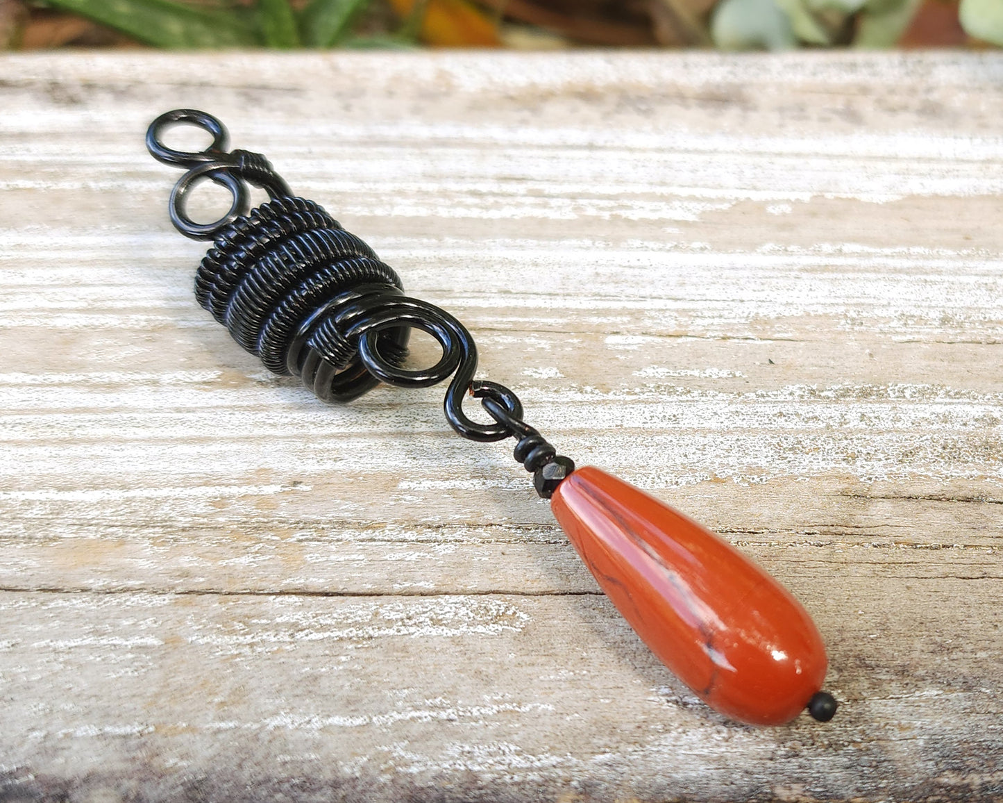 Red Jasper Tear Drop Loc Bead on a wood background.