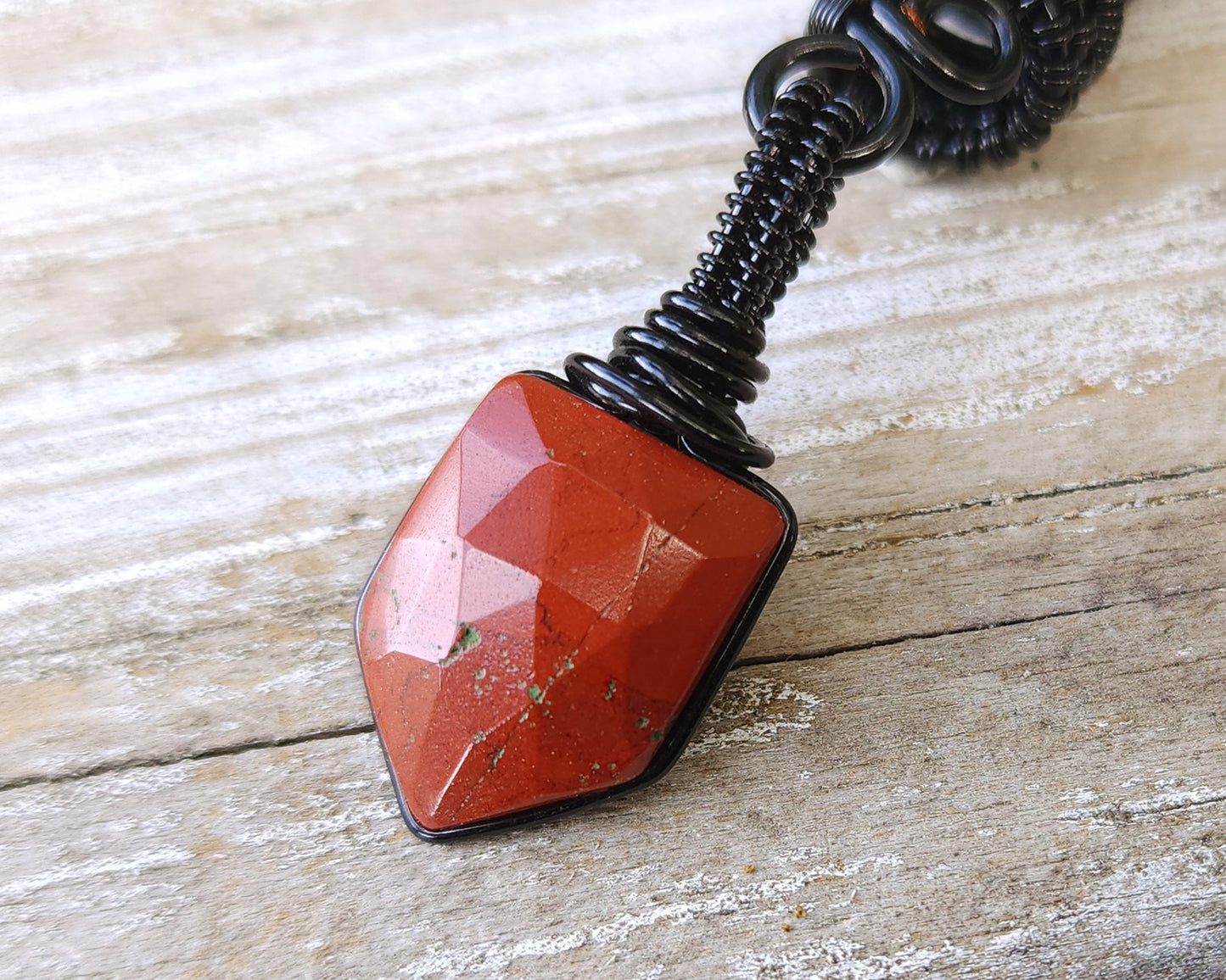 Fancy Rose Cut Red Jasper Loc Bead on a wood background.
