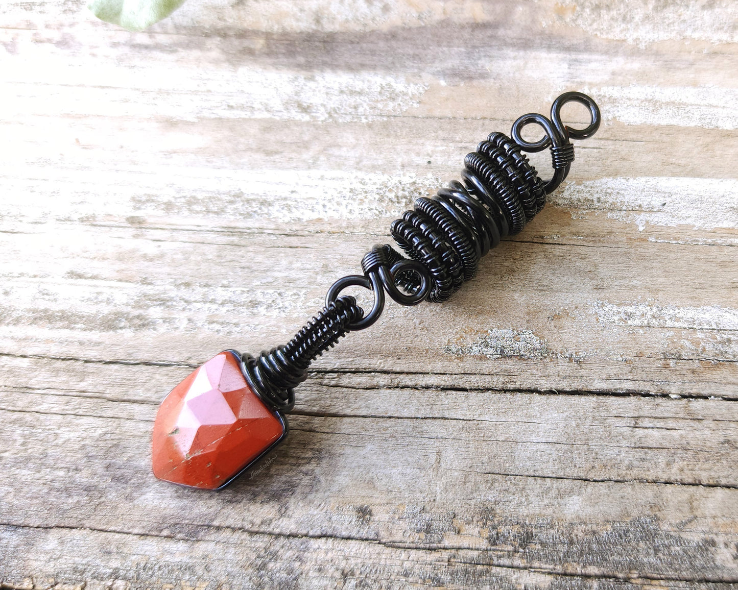 Fancy Rose Cut Red Jasper Loc Bead on a wood background.