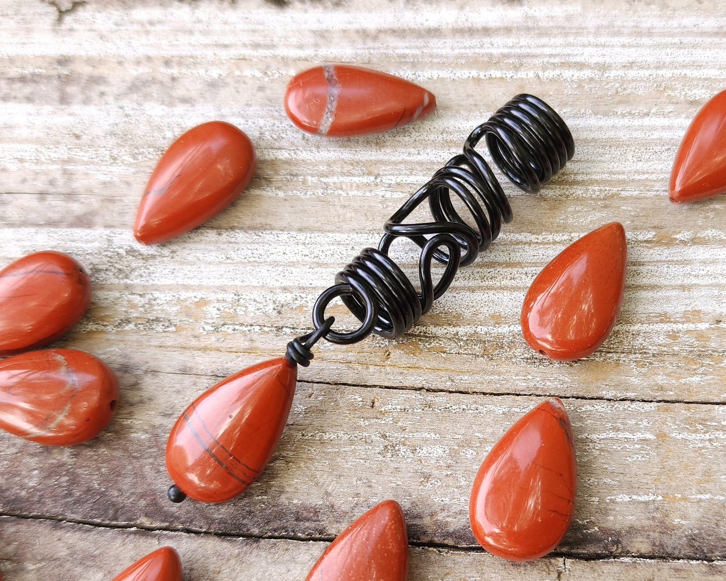 Red Jasper Flat Tear Drop Loc Bead on a wood background.