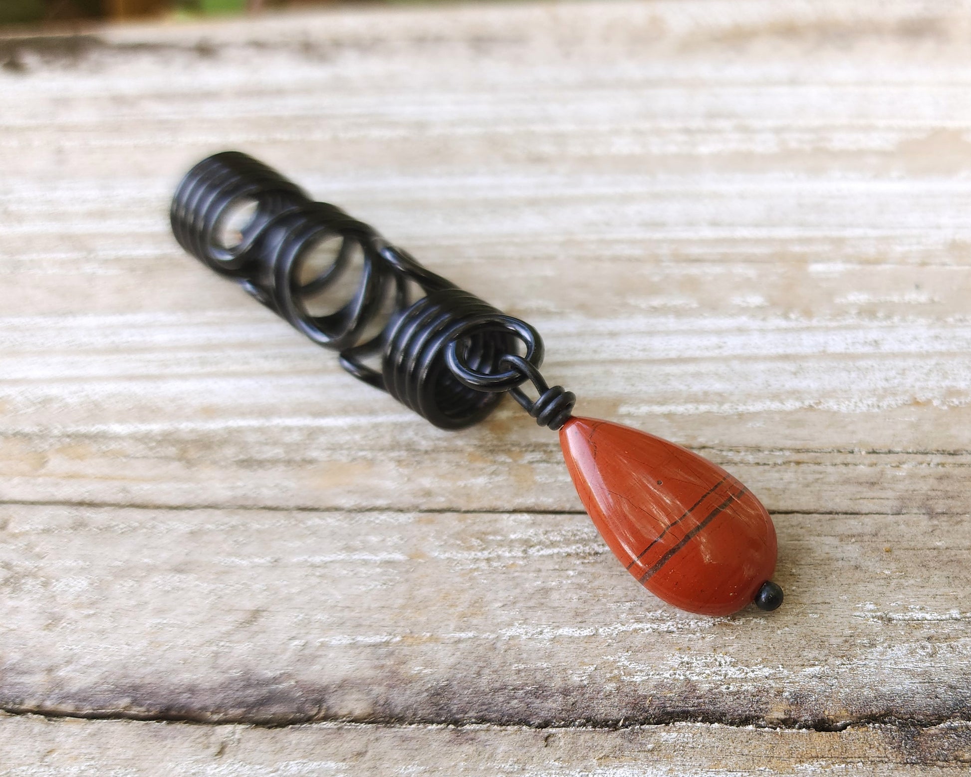 Red Jasper Flat Tear Drop Loc Bead on a wood background.