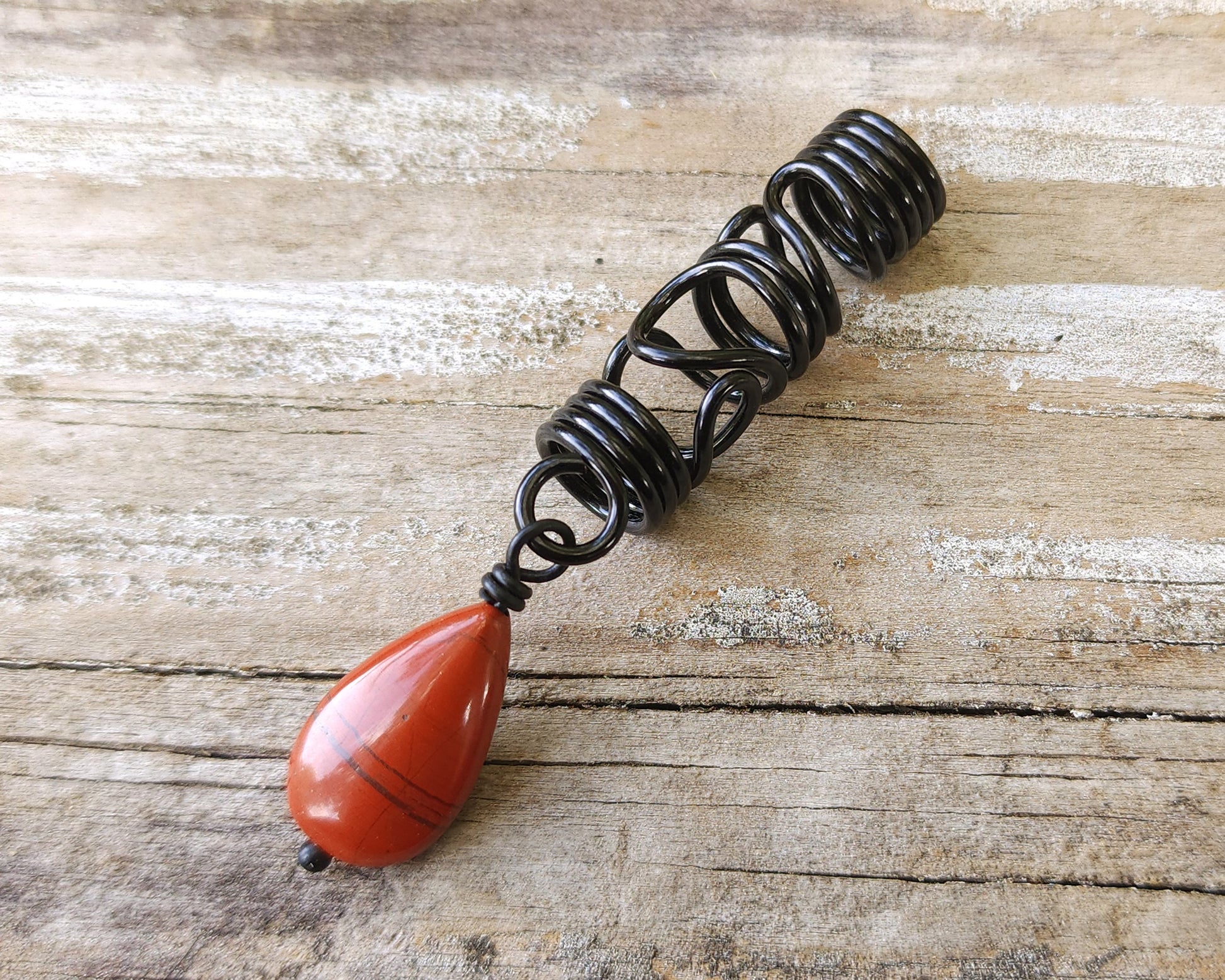 Red Jasper Flat Tear Drop Loc Bead on a wood background.
