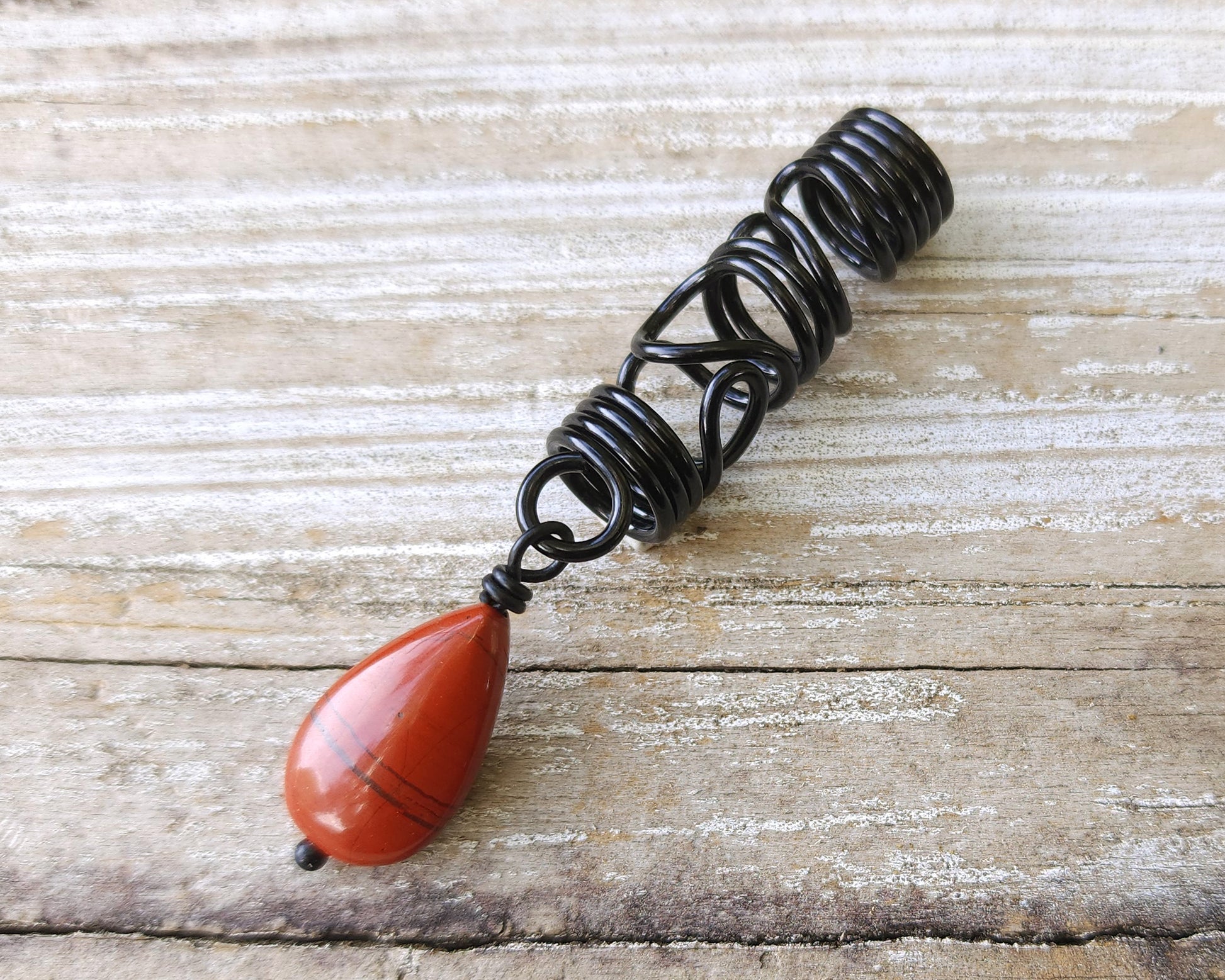 Red Jasper Flat Tear Drop Loc Bead on a wood background.