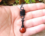 Round Cut Red Jasper Loc Bead held in hand to show scale.