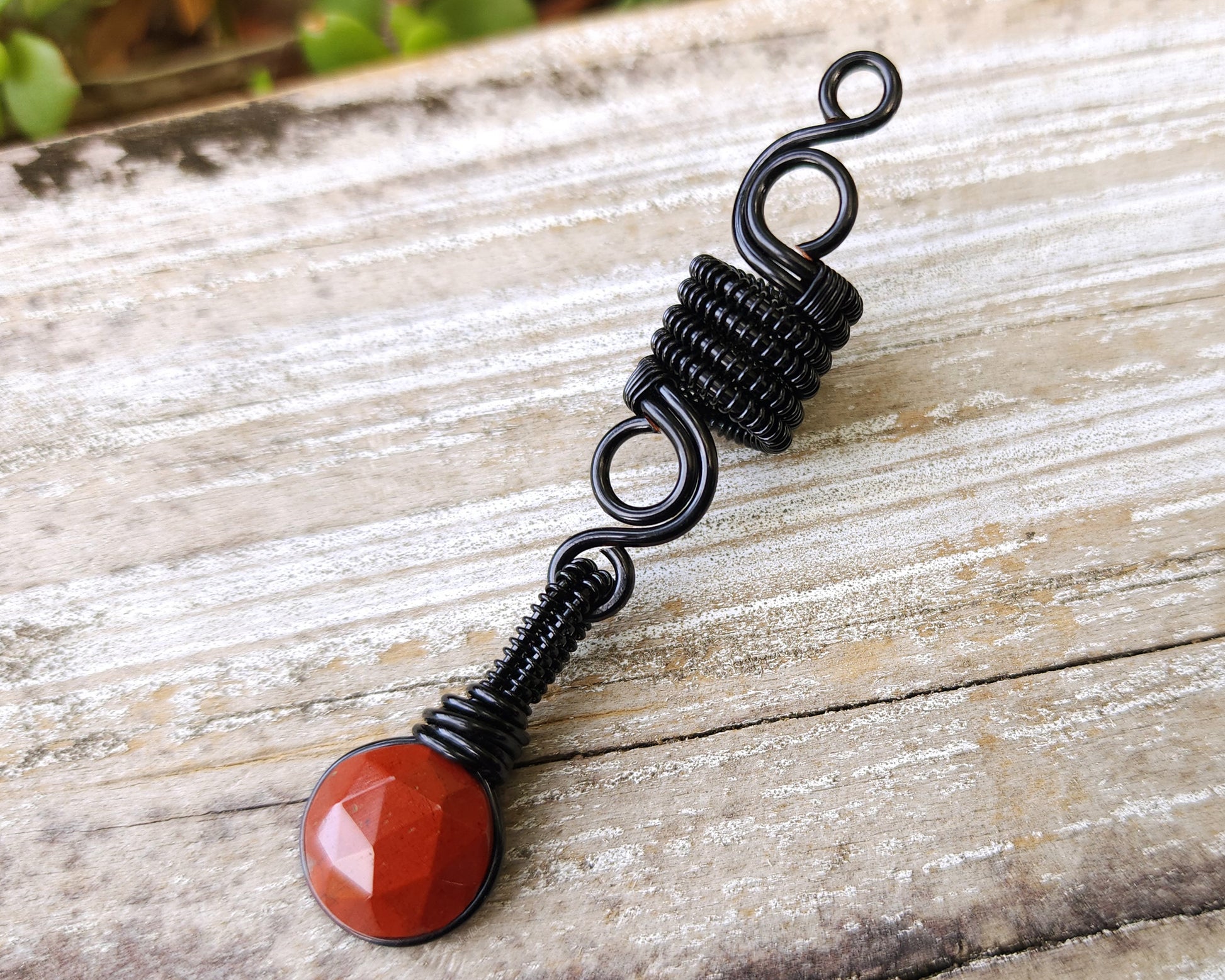 Round Cut Red Jasper Loc Bead on wood background.