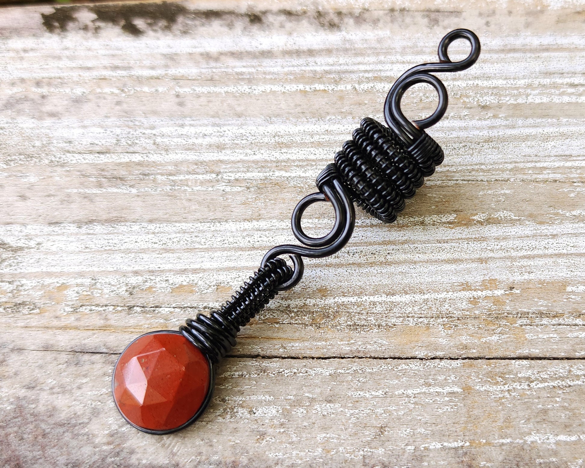 Round Cut Red Jasper Loc Bead on wood background.