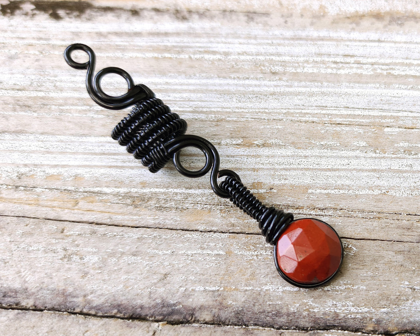 Round Cut Red Jasper Loc Bead on wood background.