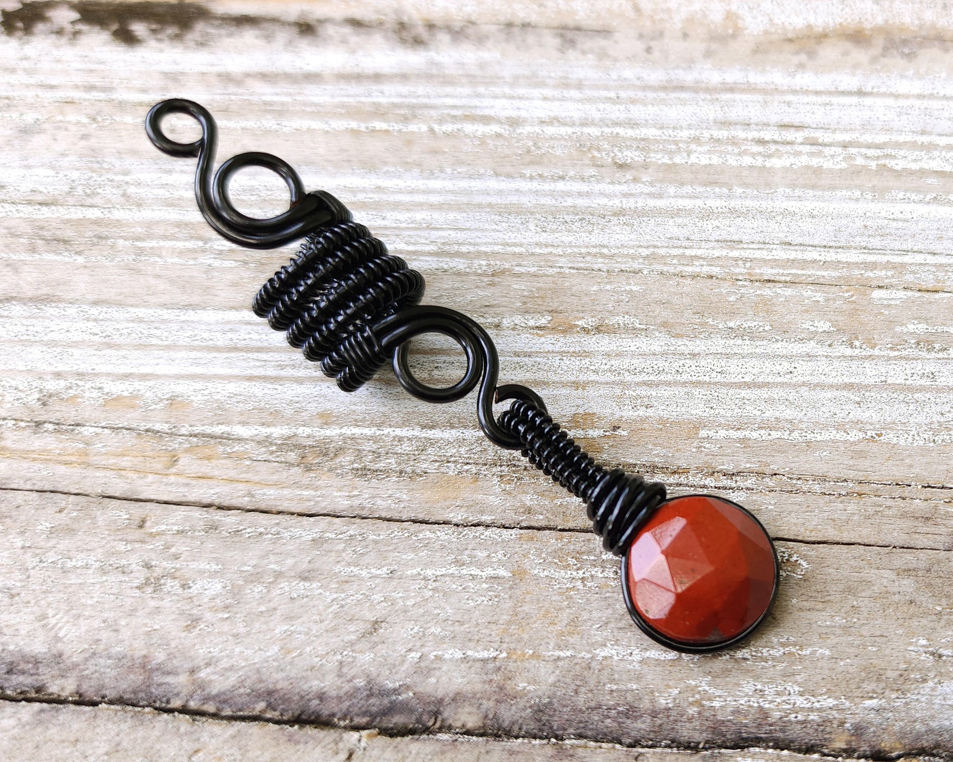 Round Cut Red Jasper Loc Bead on wood background.