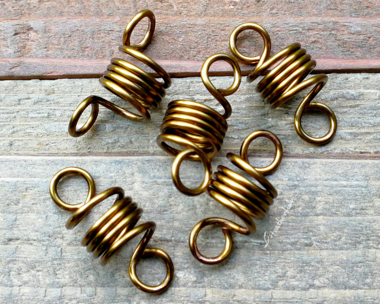A set of 5 hair beads on a wood background.