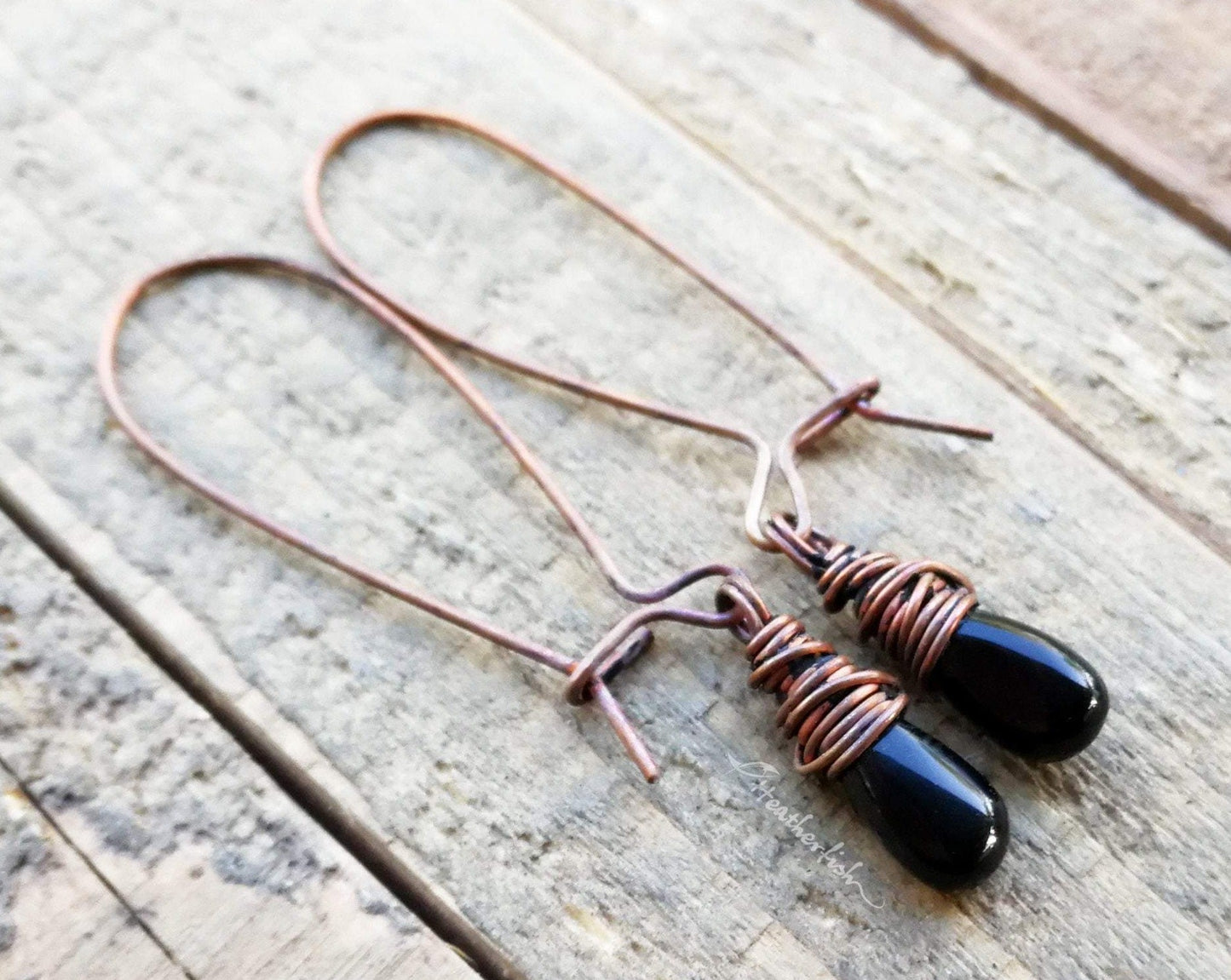 A pair of Black Onyx Earrings on a wooden background.