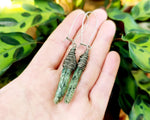 Green kyanite earrings wrapped with fine silver filled wire. Held in hand to show scale.