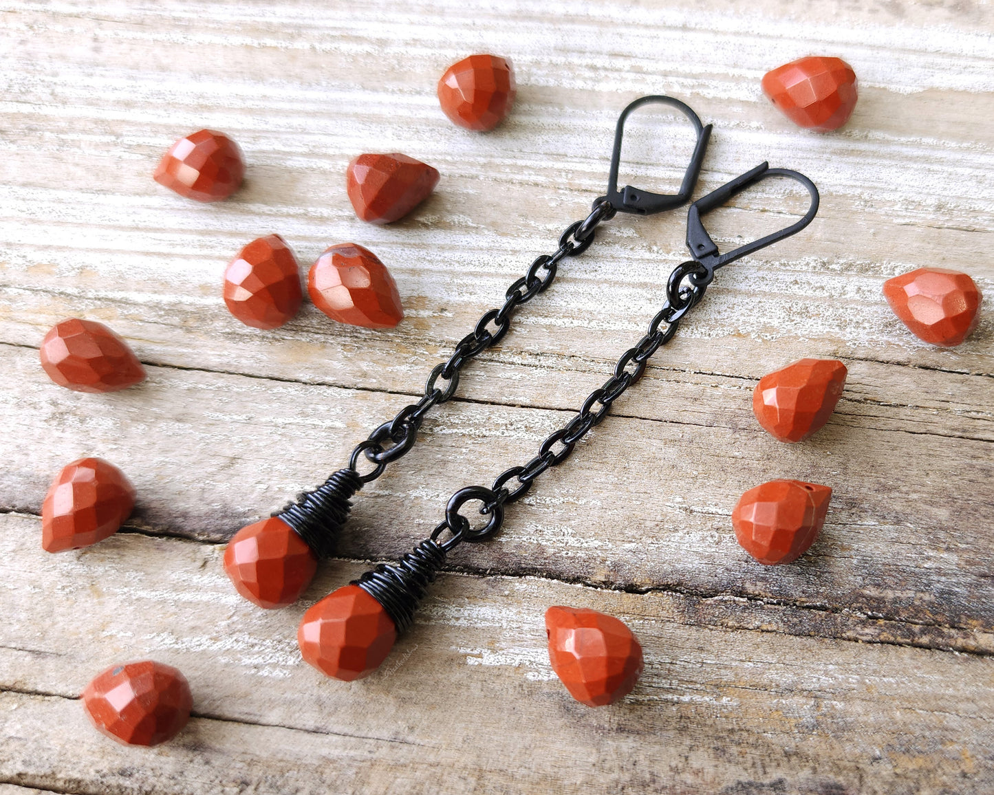 Red Jasper Earrings with black findings on a wood background.