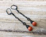 Red Jasper Earrings with black findings on a wood background.