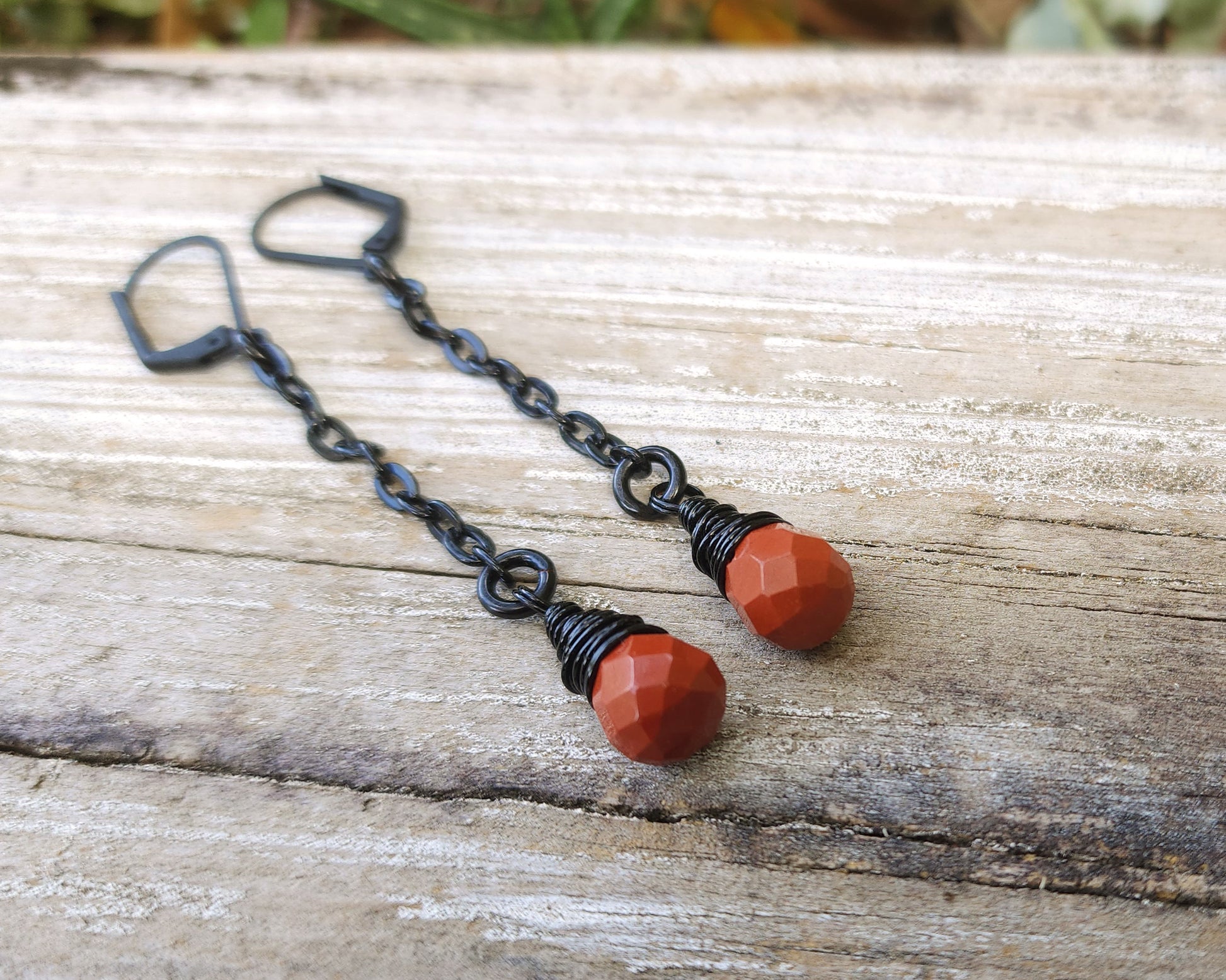 Red Jasper Earrings with black findings on a wood background.