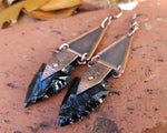 Obsidian Arrowhead Copper Earrings on brick background.