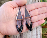 Obsidian Arrowhead Copper Earrings held in hand to show scale.